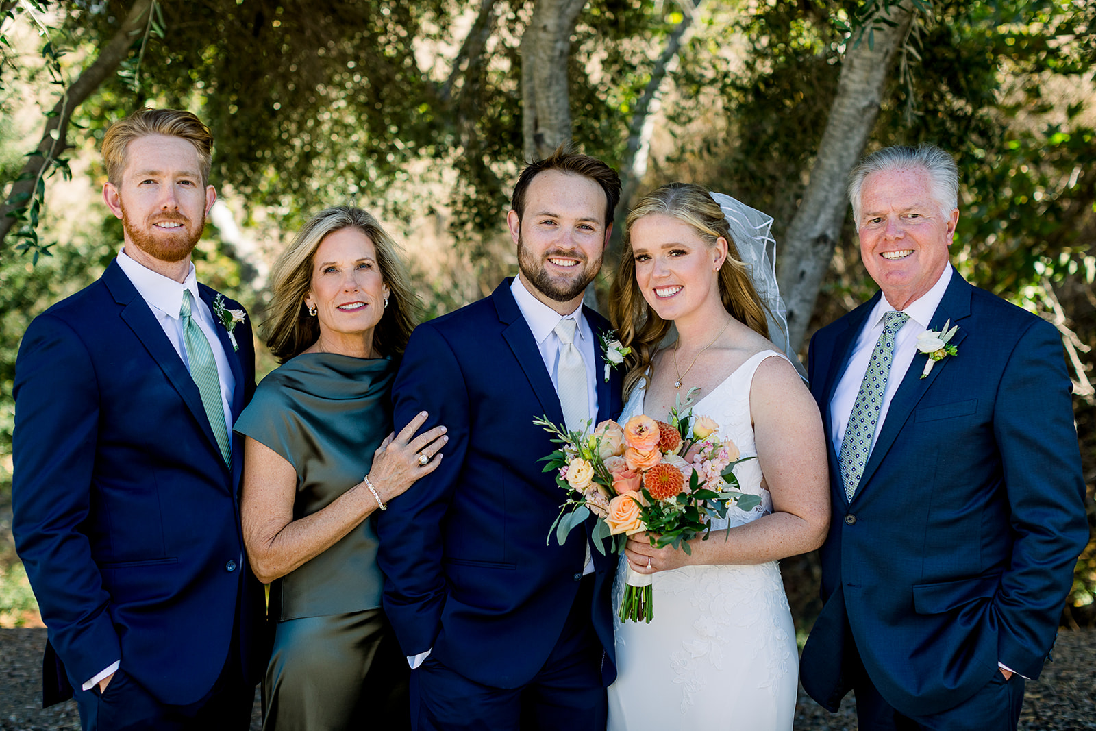 A heartwarming family photo featuring the bride and groom on their wedding day at Higuera Ranch. The couple is surrounded by loved ones, sharing smiles and joy, capturing a beautiful moment of togetherness amidst the rustic charm of the ranch setting